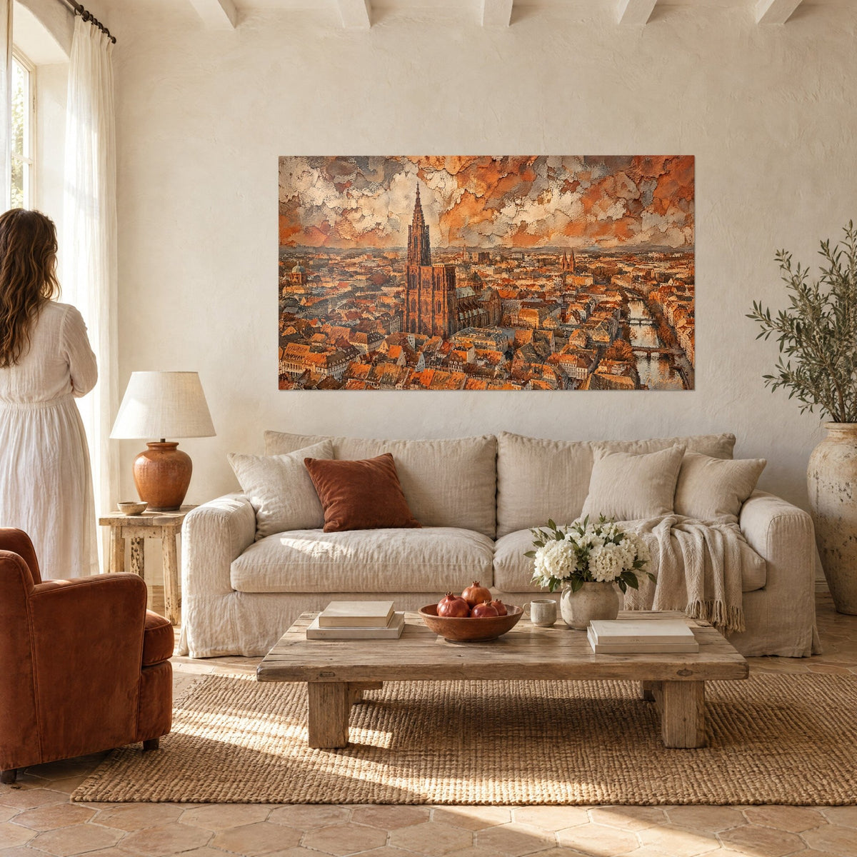 Gemälde einer gotischen Turmspitze, die über die rostroten Dächer der Stadt ragt, rissiger cremefarbener Himmel, oberhalb eines Sofas in einem hellen Wohnzimmer