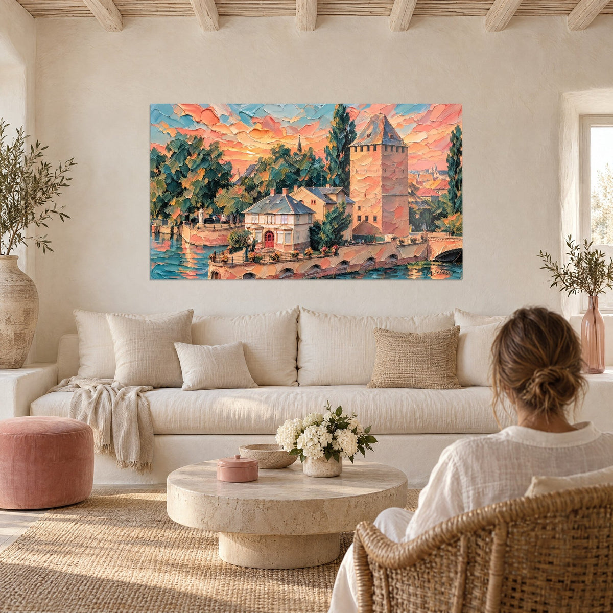 Gemälde Turm mit Zinnen in Rosa und Ocker unter einem orangefarbenen Abendhimmel, Paar von hinten über einem Sofa in einem hellen Wohnzimmer