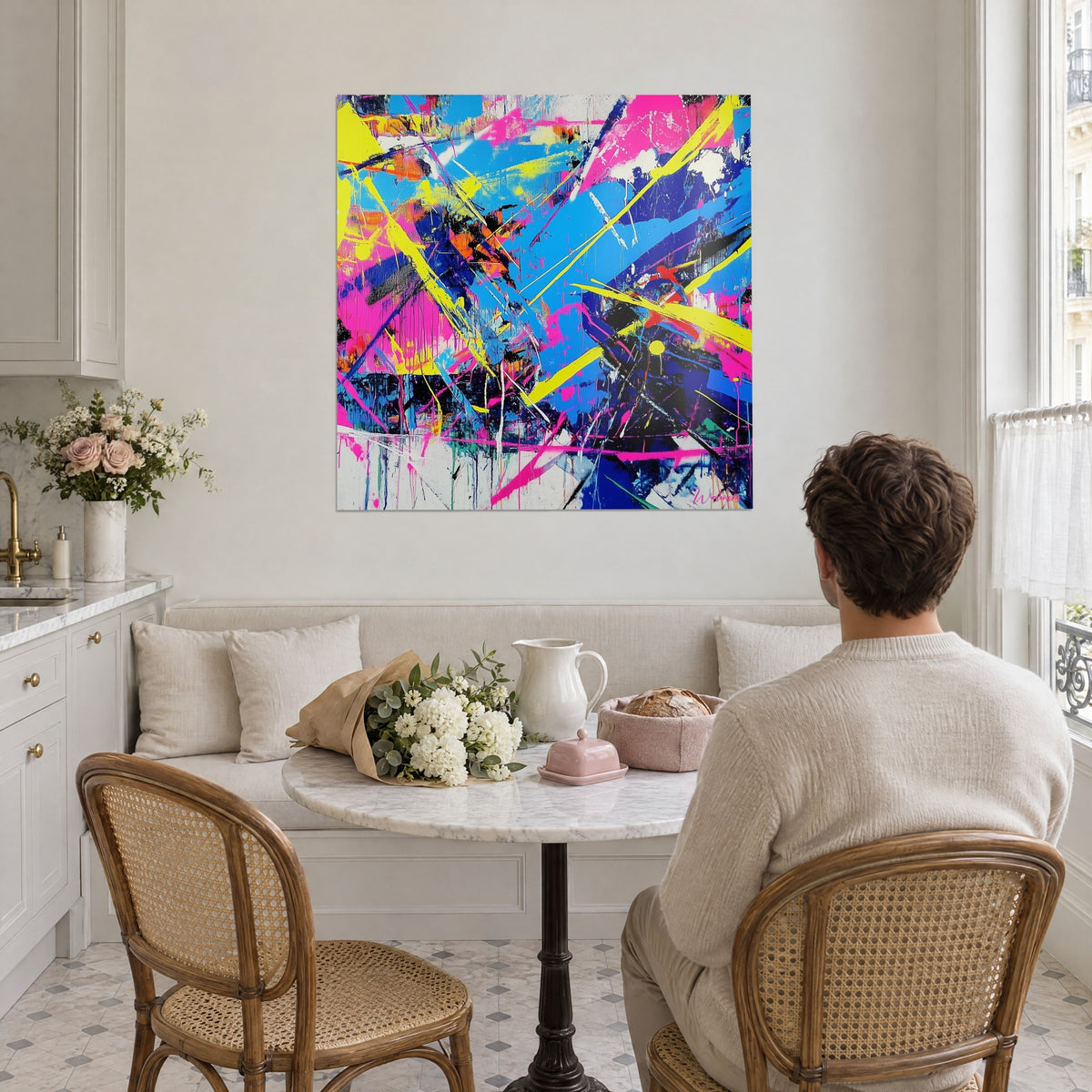 Cuadro lienzo abstracto con salpicaduras blancas, azul vivo y rosa neón, frente a una mesa redonda en una cocina haussmanniana