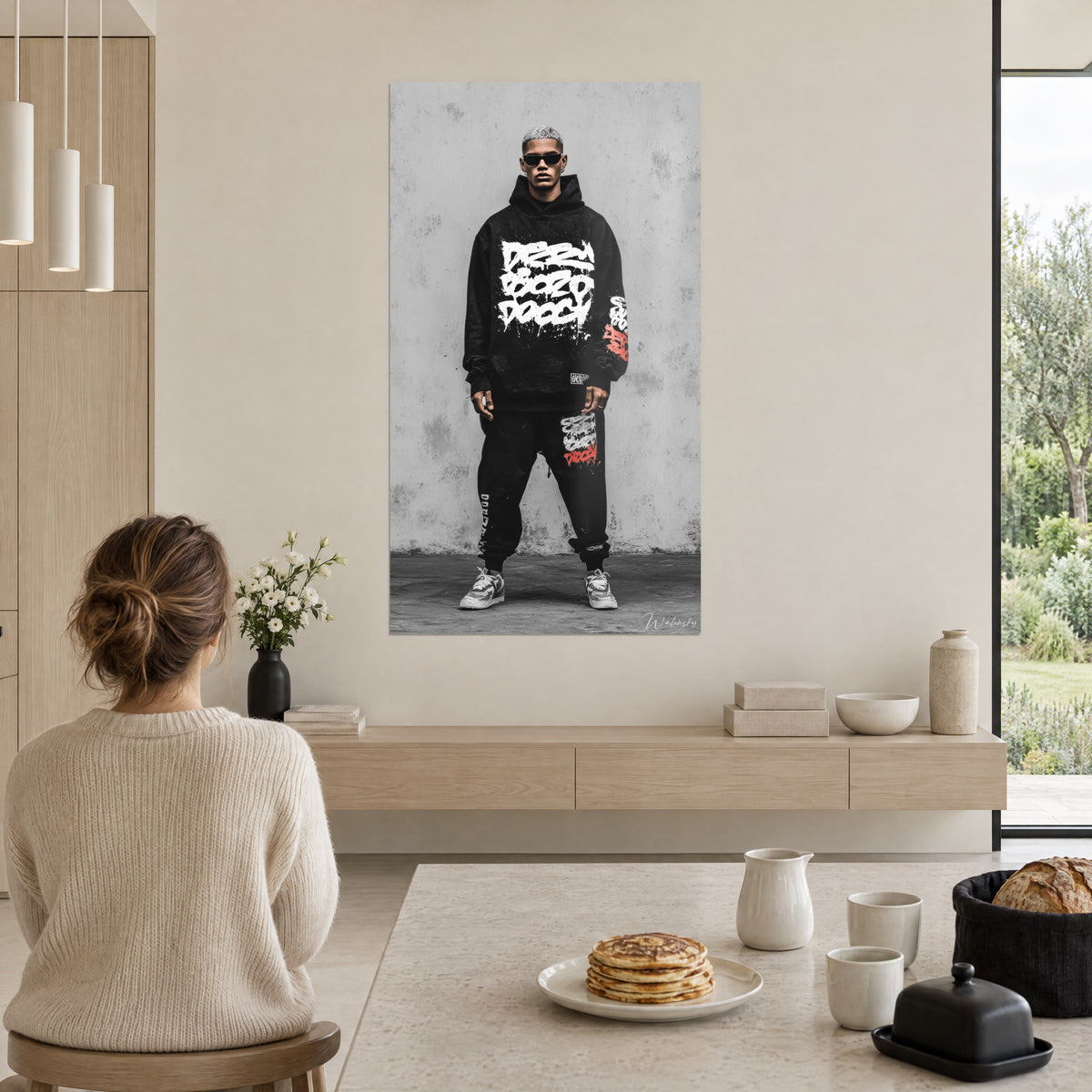 Cuadro de un look hip-hop, sudadera negra con letras blancas, zapatillas grises, hormigón claro, visto desde una mesa de desayuno beige y blanca