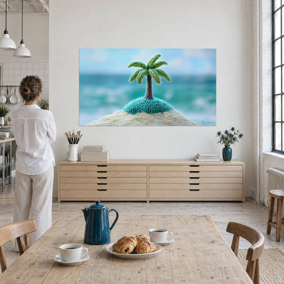 Wall art turquoise knitted atoll topped with a green palm tree, blurred ocean, woman in a white shirt seen from behind in a loft