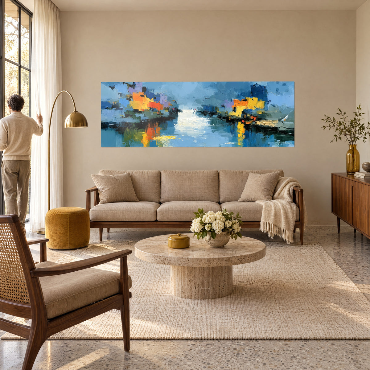 Gemälde Hafenmotiv abstrakt mit orangefarbenen und gelben Fassaden, die sich im blauen Wasser spiegeln, Rückenfigur eines Mannes über einem Sofa in einem hellen Wohnzimmer