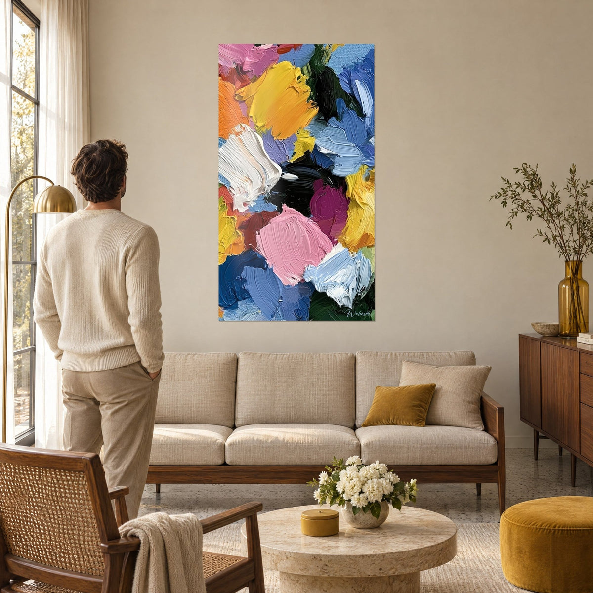 Cuadro con pinceladas de espátula en amarillo y rosa en abanico, azul cremoso y blanco, hombre de espaldas, sobre un sofá en un salón luminoso