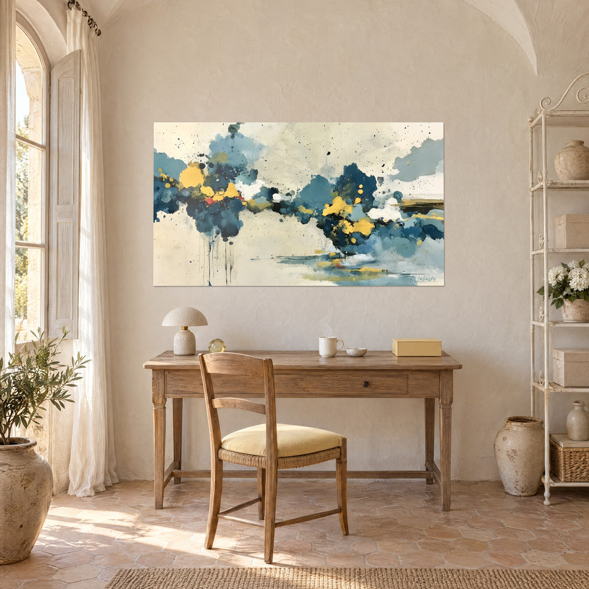 Wall art of an abstract landscape with midnight-blue drips and saffron yellow accents, hung above a wooden desk in a farmhouse