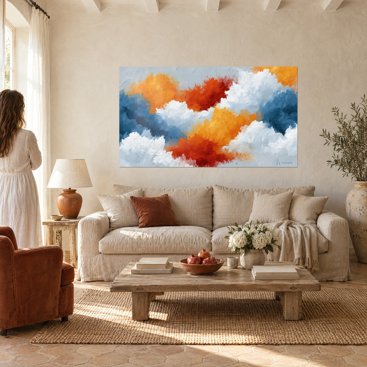 Gemälde Wolkenformationen in Marineblau und glühendem Orange mit pastosem Farbauftrag, gehängt über einem Sofa in einem hellen Wohnzimmer vor einer Frau von hinten