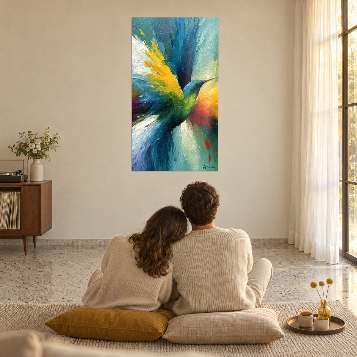 Tableau colibri butineur en pleine envolée, dégradés bleu roi, citron et corail, couple de dos assis sur des coussins moutarde, salon vitré