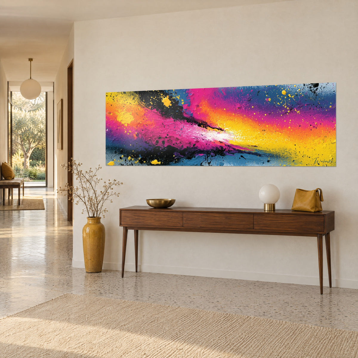 Schilderij verfexplosie in fuchsiaroze en zonnegeel, zwarte druppels verspreid, aan een beige muur boven een console