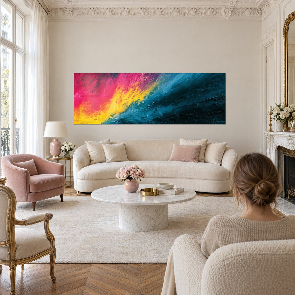 Wall art with a diagonal wave of pink and yellow melting into teal blue, a woman seen from behind, above a sofa in a bright living room