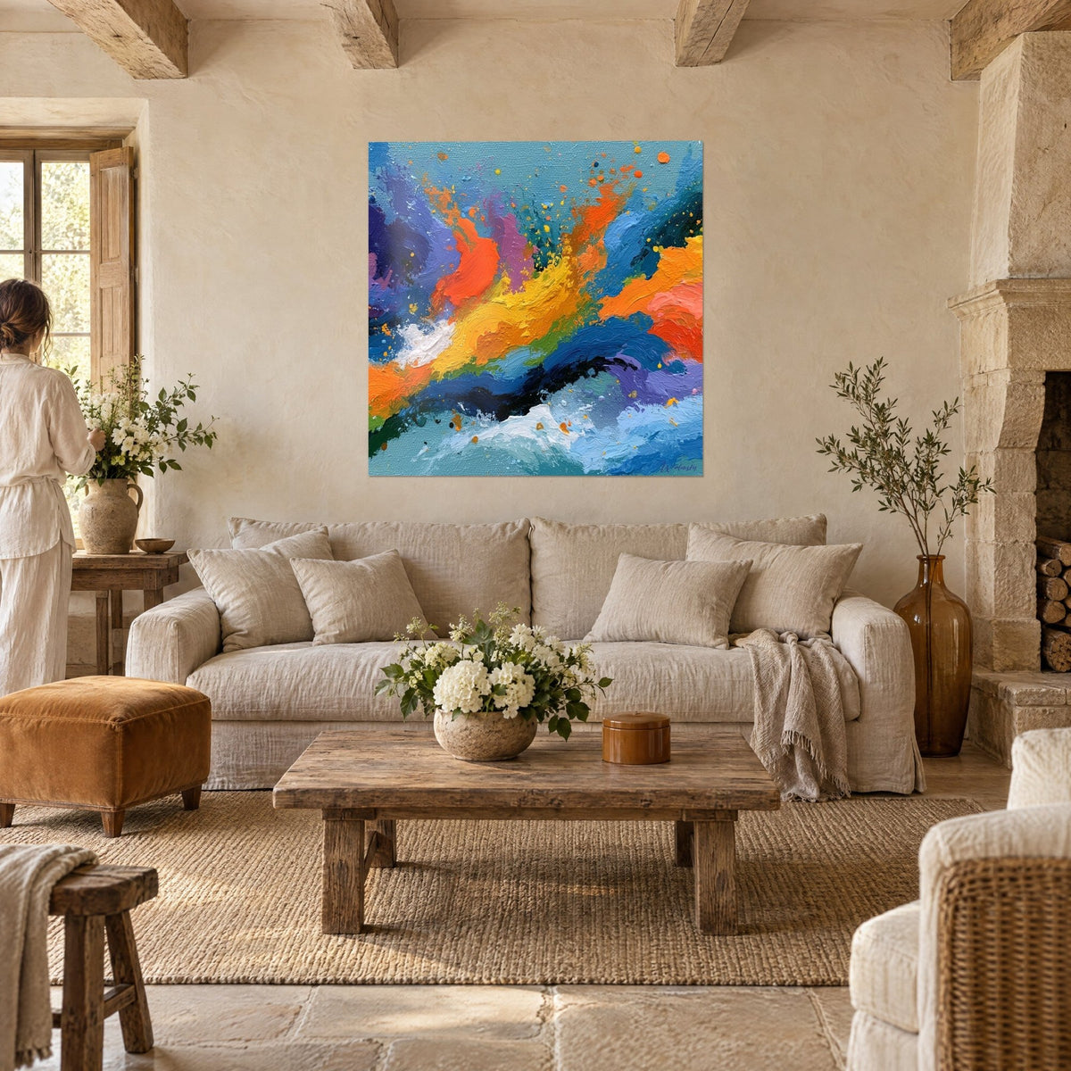 Wall art with an eruption of orange and yellow paint on a turquoise background, a woman seen from behind, above a sofa in a bright living room