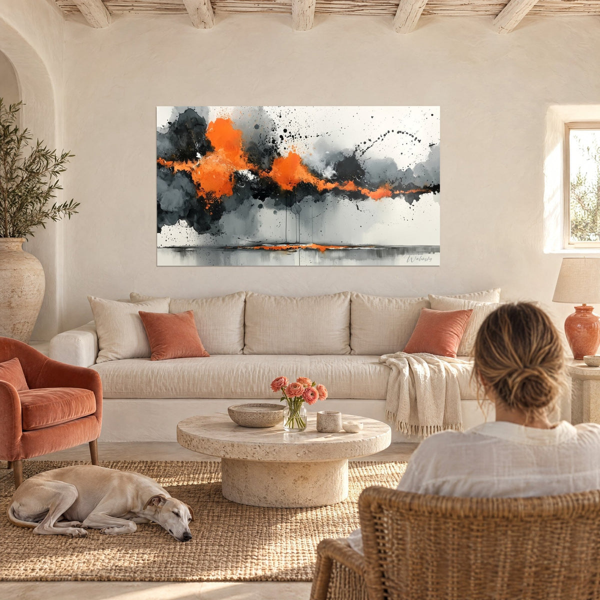 Gemälde mit orangefarbenen und anthrazitfarbenen Spritzern auf weißem Grund, Frau von hinten und liegender Windhund, über einem Sofa in einem hellen Wohnzimmer