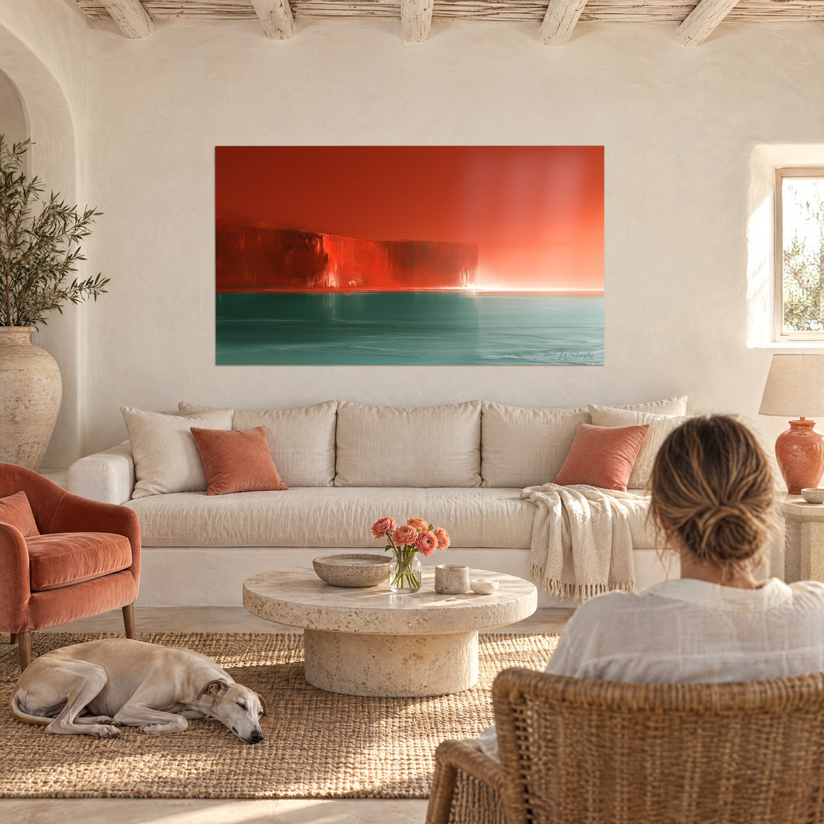 Tableau falaise écarlate dressée sur une mer sarcelle, ciel orangé, femme de dos et lévrier, au-dessus d'un canapé dans un salon lumineux
