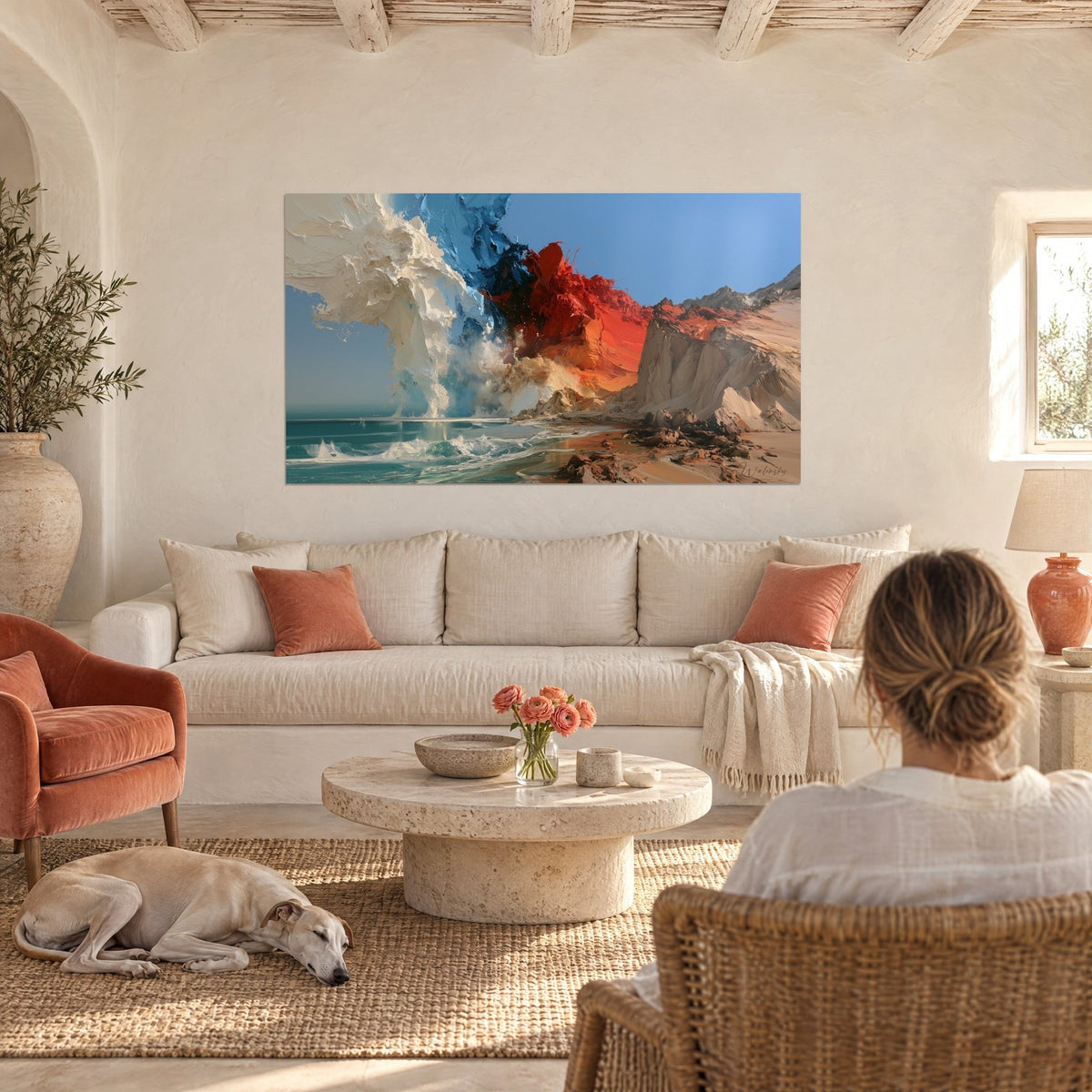 Wall art red and white cliff on a sandy beach, a woman and a greyhound seen from behind, above a sofa in a bright living room