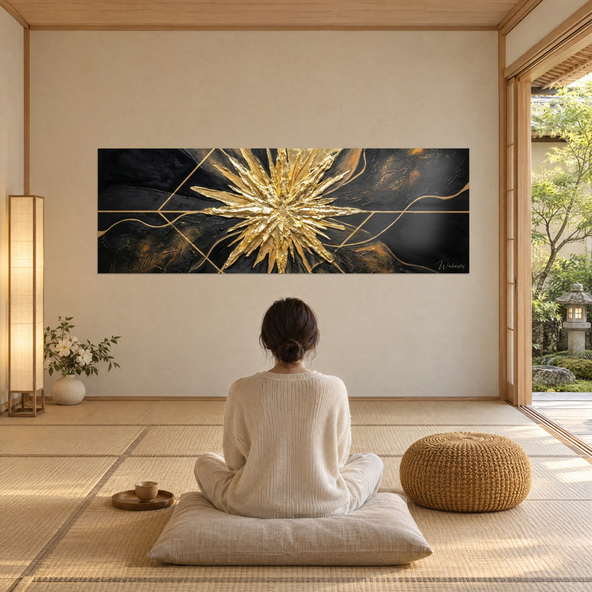 Tableau constellation dorée aux pointes ciselées sur fond noir et cuivre, femme de dos assise en méditation sur un coussin crème