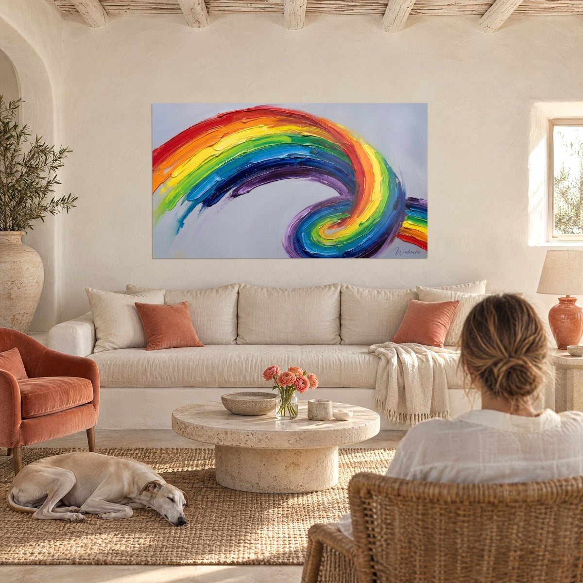 Schilderij met regenboogspiraal van dikke verfpartijen in rood, geel en blauw, twee figuren van achteren, boven een bank in een lichte woonkamer