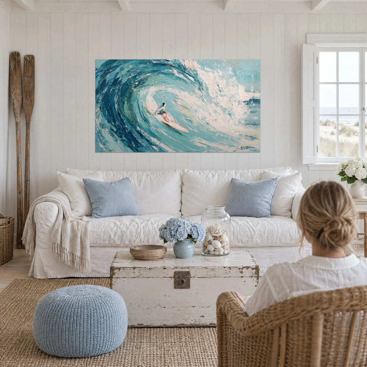 Wall art surfer gliding through a turquoise tube, white foam and navy blue, above a sofa in a bright living room