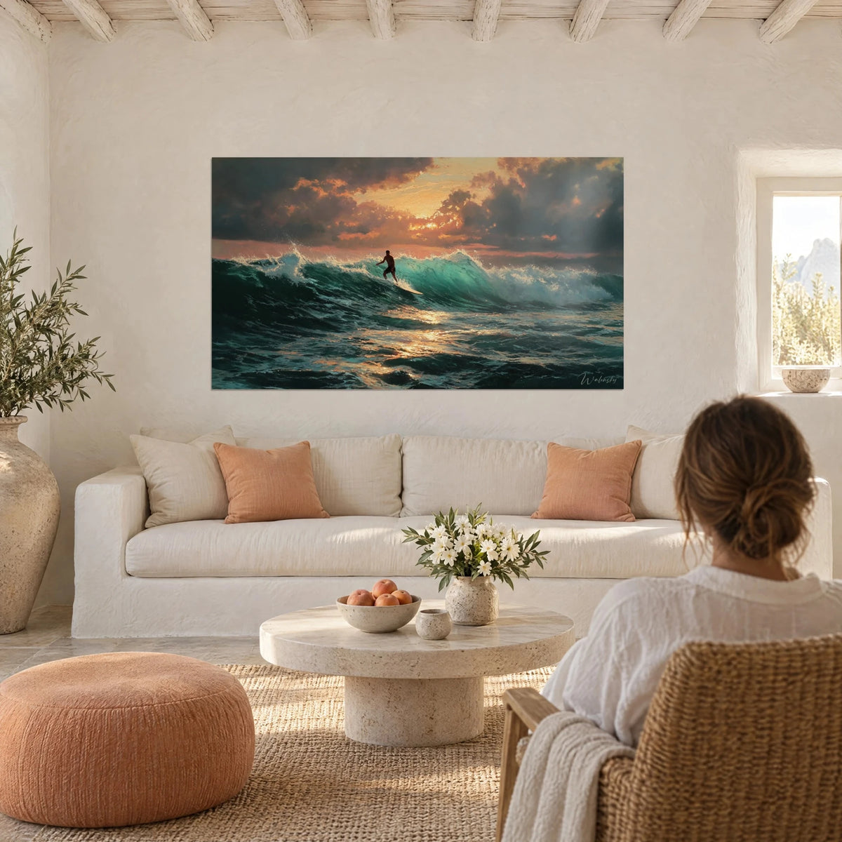 Schilderij surfer die over een turquoise golf glijdt, oranje lucht en donkere wolken, vrouw van achteren boven een bank in een lichte woonkamer