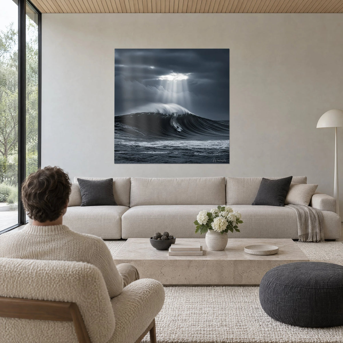 Gemälde winziger Surfer, der eine anthrazitfarbene Welle unter silbernen Lichtstrahlen hinabgleitet, über einem Sofa in einem hellen Wohnzimmer