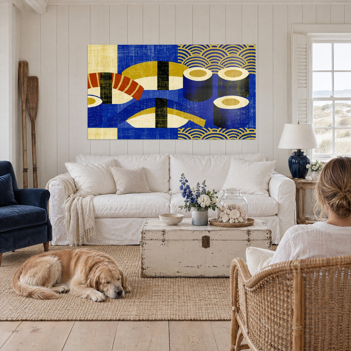 Cuadro de sushis geométricos en azul marino y dorado, nigiri de salmón anaranjado, un retriever tumbado, sobre un sofá en un salón luminoso