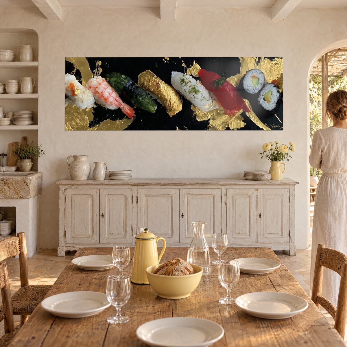 Tableau nigiri doré à la feuille d'or près d'une crevette orangée sur noir, une femme de dos dans une salle à manger provençale