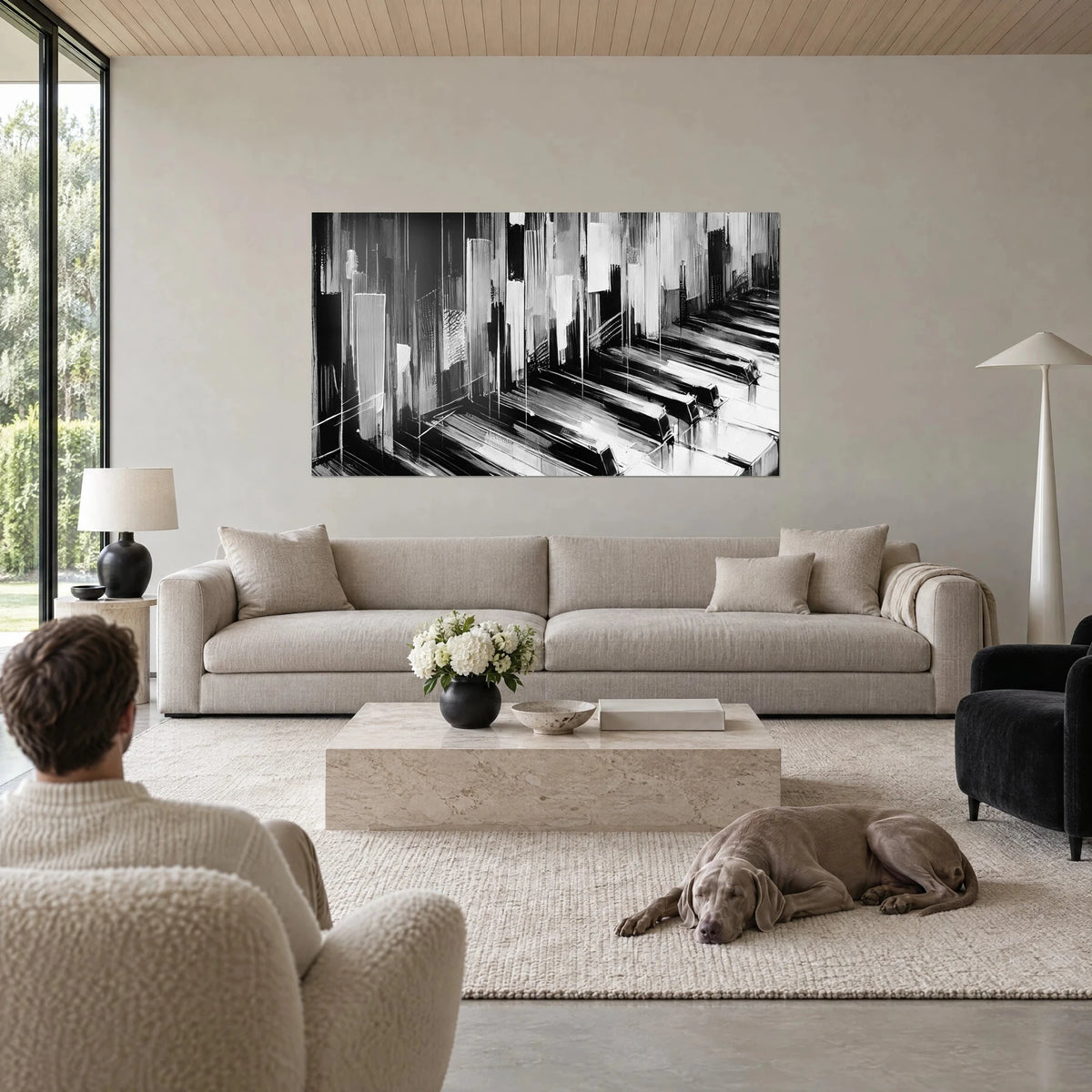 Schilderij abstract pianoklavier in zwart-wit, verticale grijze druipsporen, man van achteren en hond, boven een bank in een lichte woonkamer