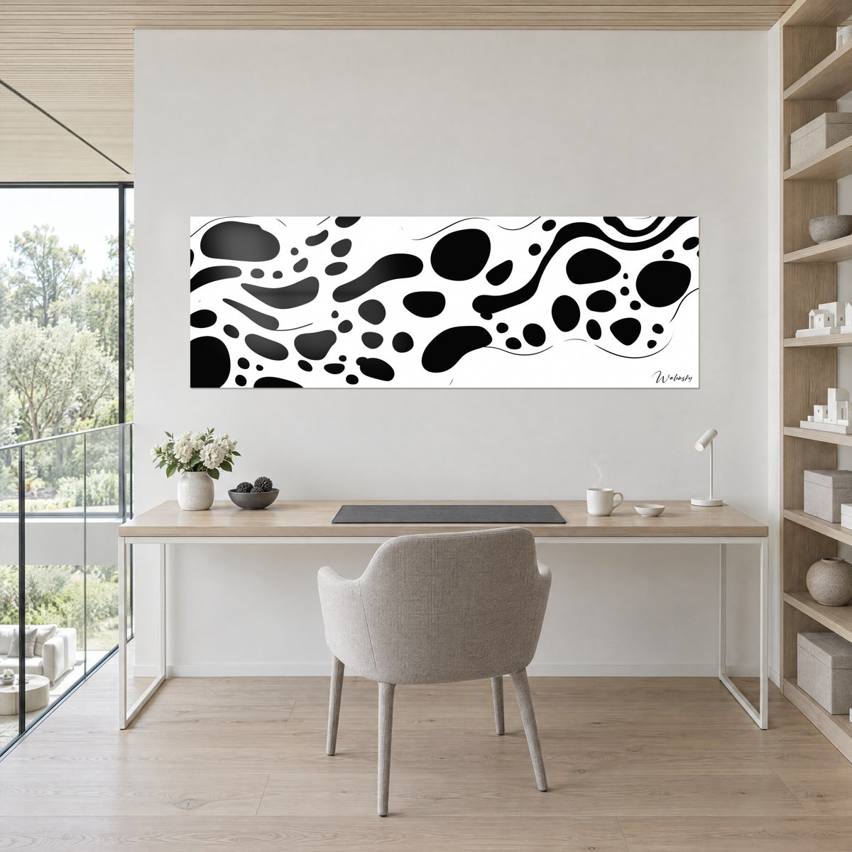 Quadro forme organiche nere e bianche in fregio orizzontale, parete crema, scrivania in legno chiaro e sedia grigia