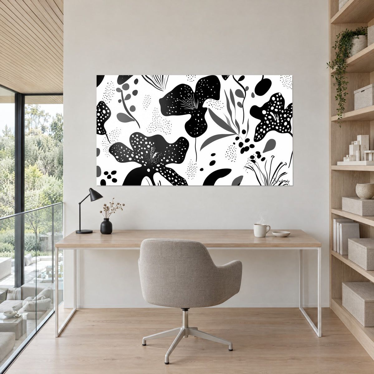 Cuadro de floración monocroma, grandes flores negras punteadas de blanco y hojas gris medio, colgado frente a un escritorio de madera clara