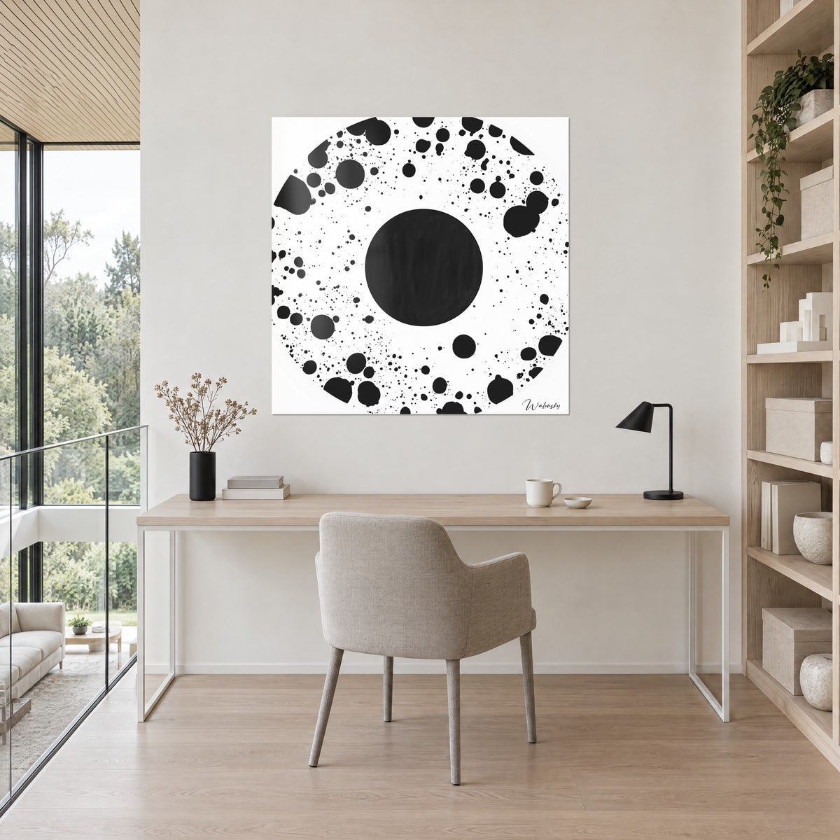 Tableau constellation de gouttes noires autour d'un rond anthracite, sur fond blanc, accroché au-dessus d'un bureau en bois clair et d'une lampe noire