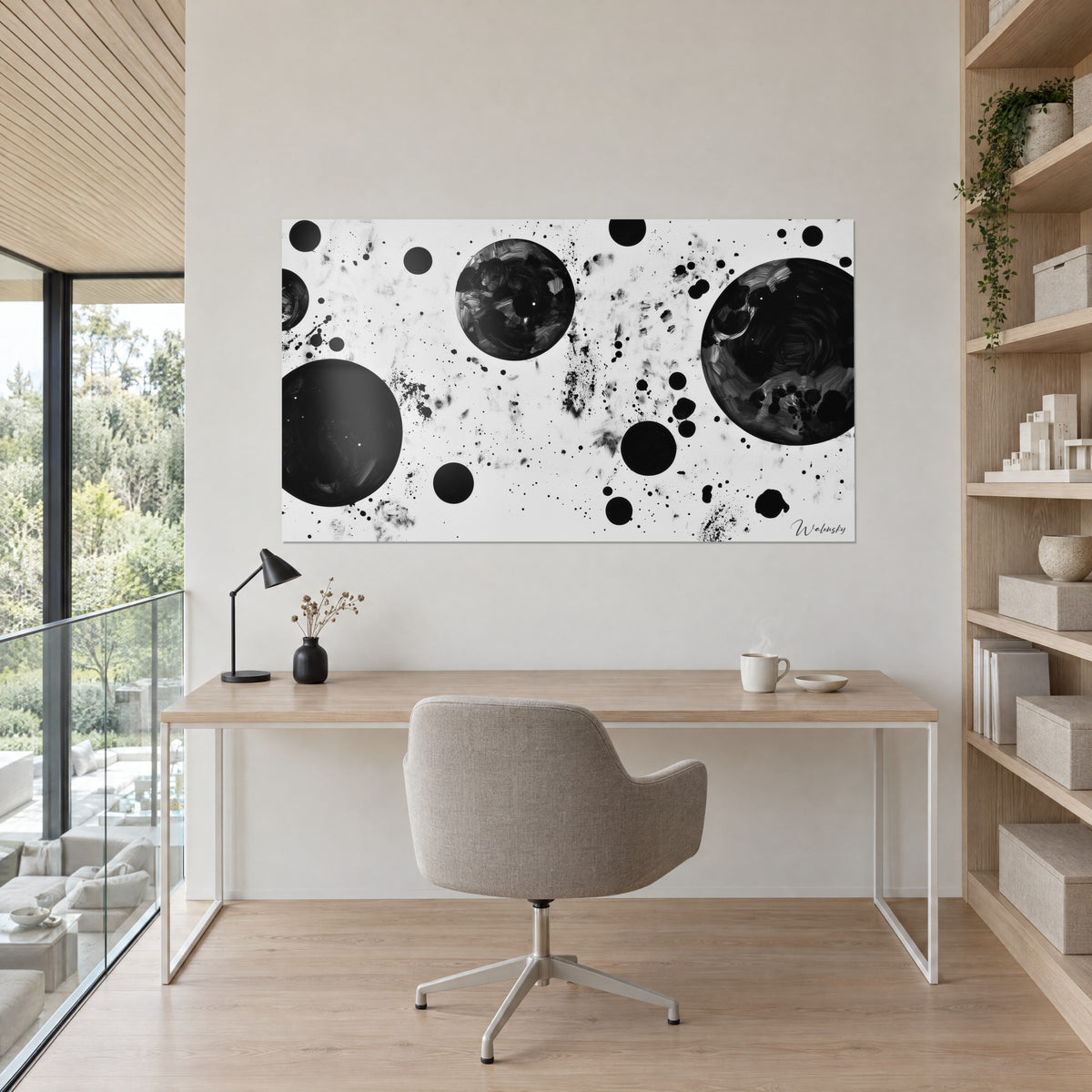 Cuadro galaxia de tinta, círculos negros surcados de reflejos plateados sobre fondo blanco, encima de un escritorio de madera clara