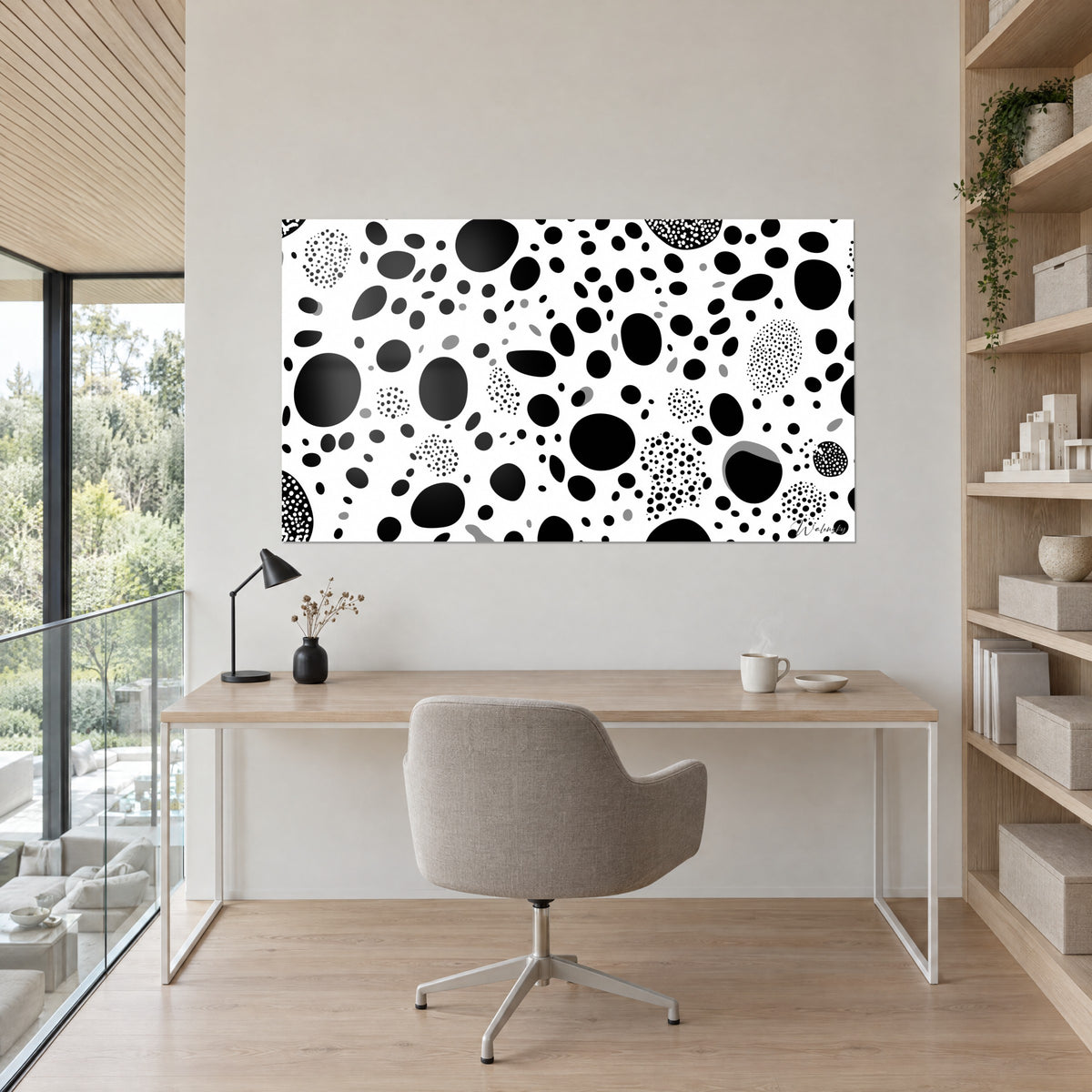 Wall art with black ink bubbles on white background, clusters of small dots and grey highlights, facing a light wood desk