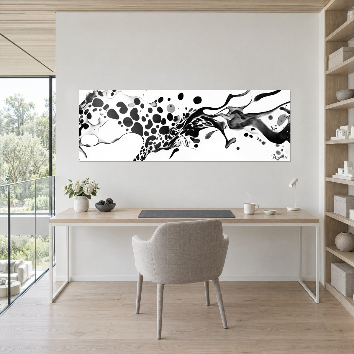 Quadro di spruzzo monocromo con macchie nere e tocchi grigi su bianco, sopra una scrivania in legno chiaro e una sedia