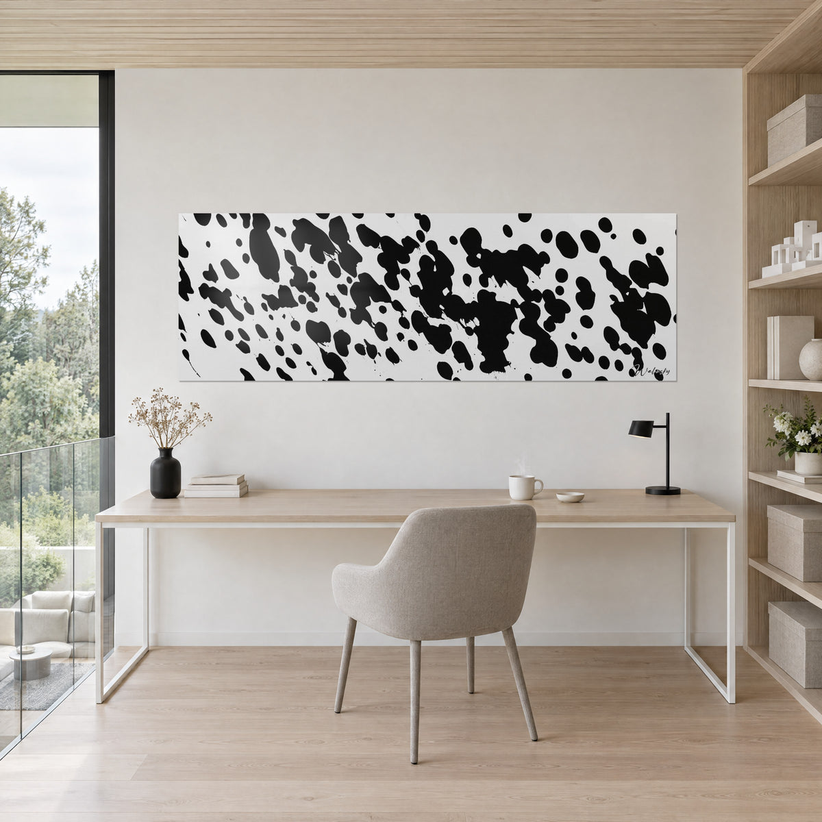 Cuadro con motivo moteado estilo dálmata, negro intenso sobre blanco, encima de un escritorio de madera clara y una silla gris
