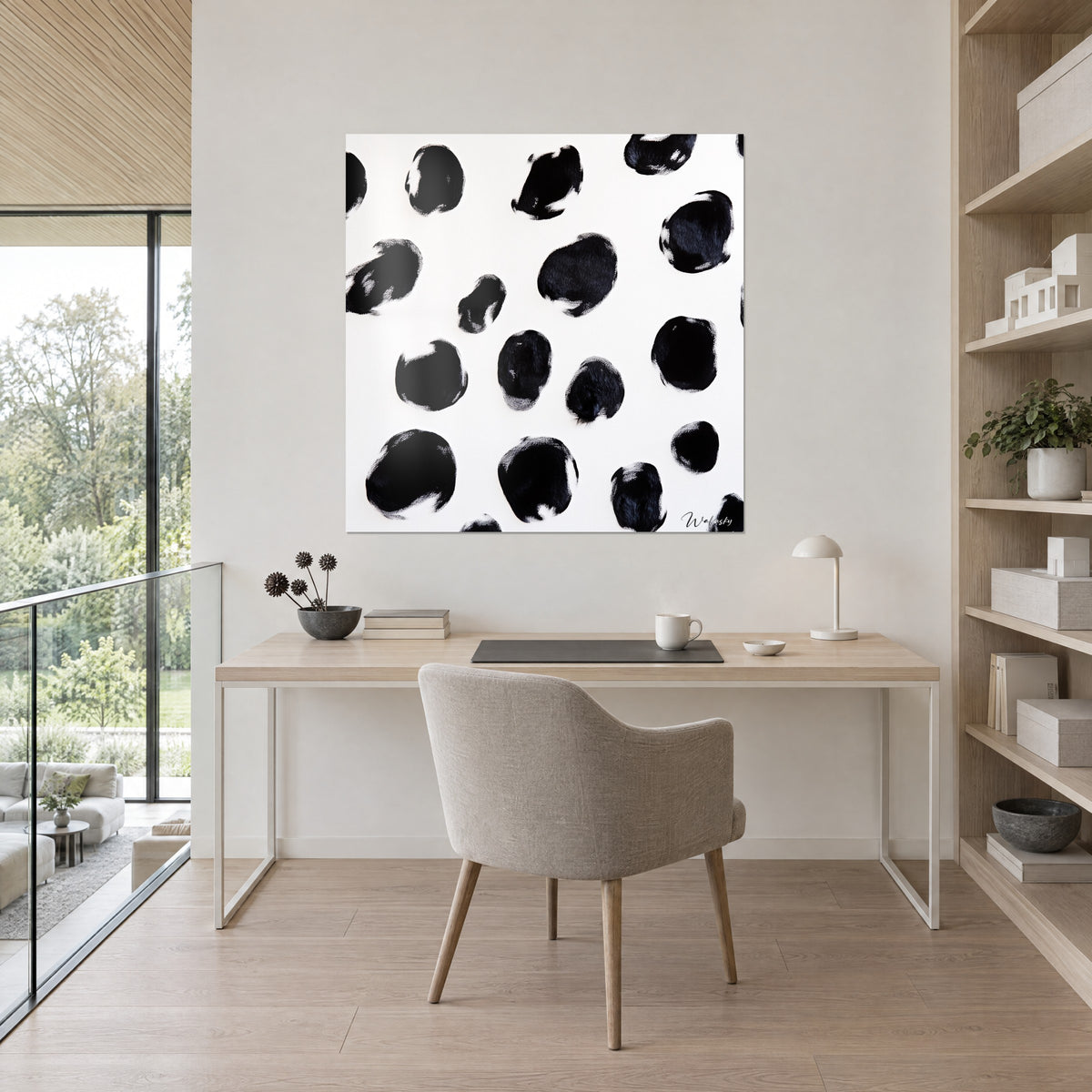 Cuadro con huellas negras carbonosas sobre blanco puro, luz suave, escritorio claro de madera y sillón gris, estanterías rubias