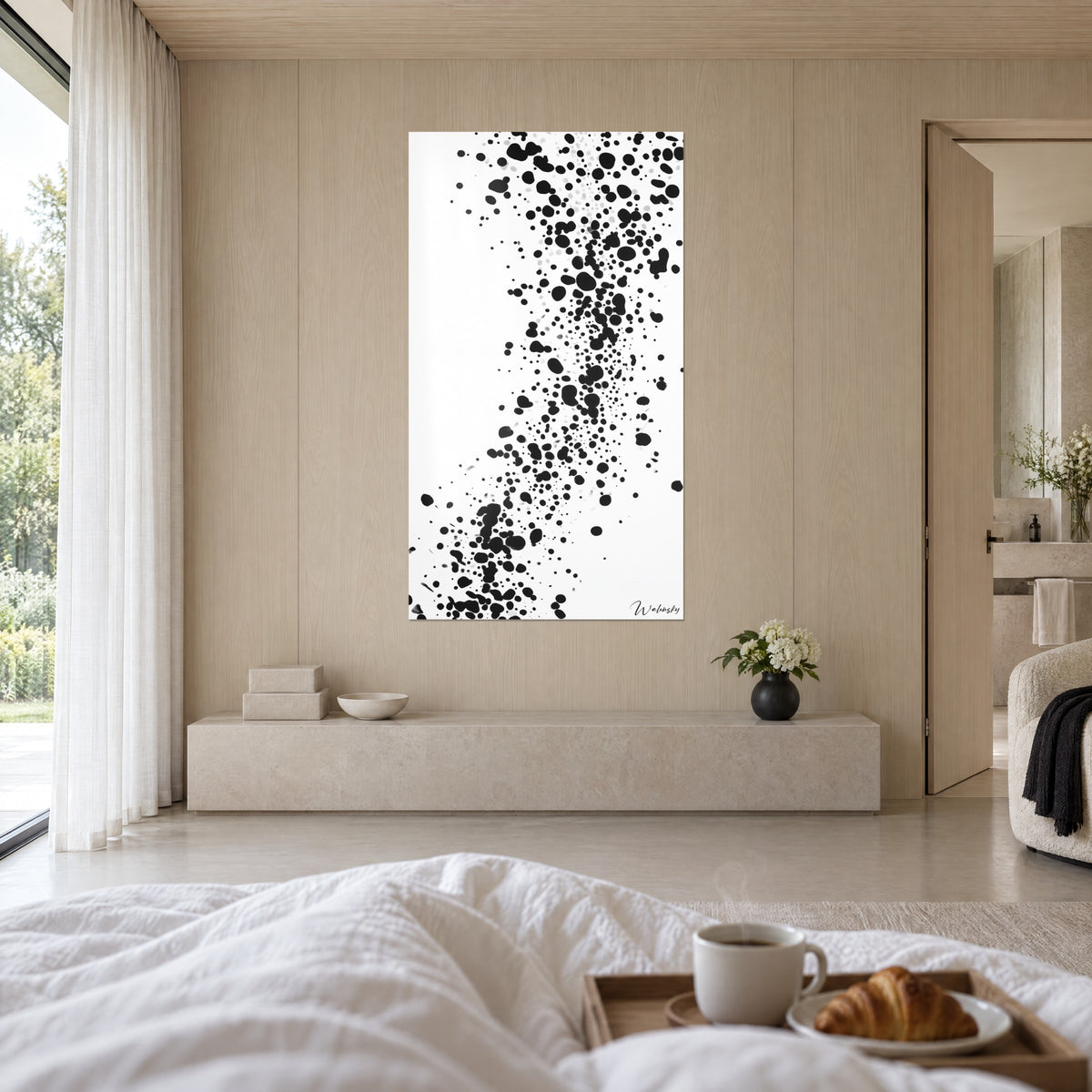 Cuadro con una nube de puntos negros sobre fondo blanco, paredes beige de madera clara, encima de una cama en un dormitorio luminoso
