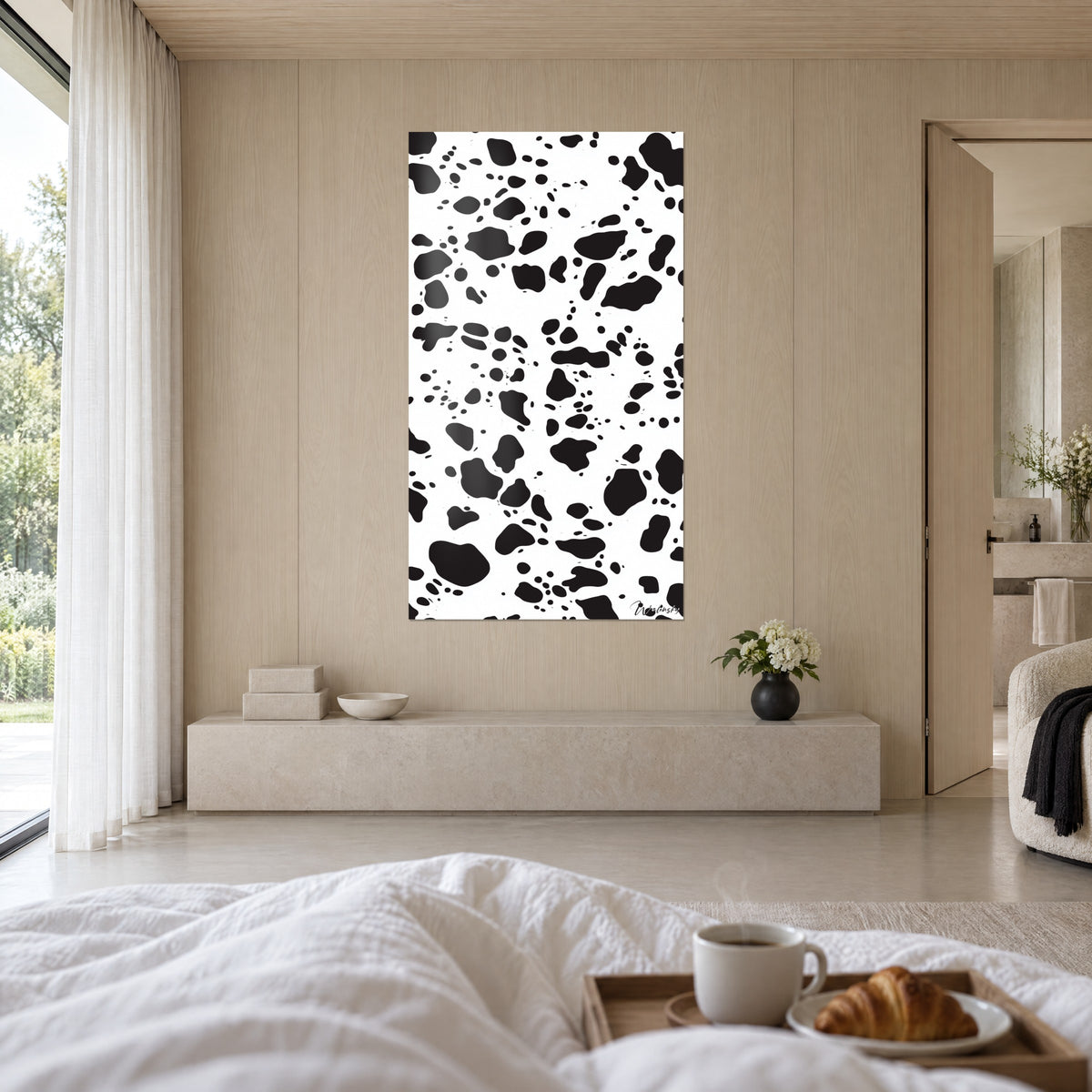Cuadro con manchas irregulares estilo piel de vaca, negro profundo y blanco puro, encima de una cama en un dormitorio claro