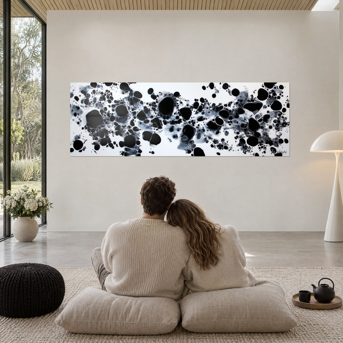 Wall art Milky Way of charcoal ink, large black bubbles and grey mist, couple embracing from behind, cream cushions, off-white wall