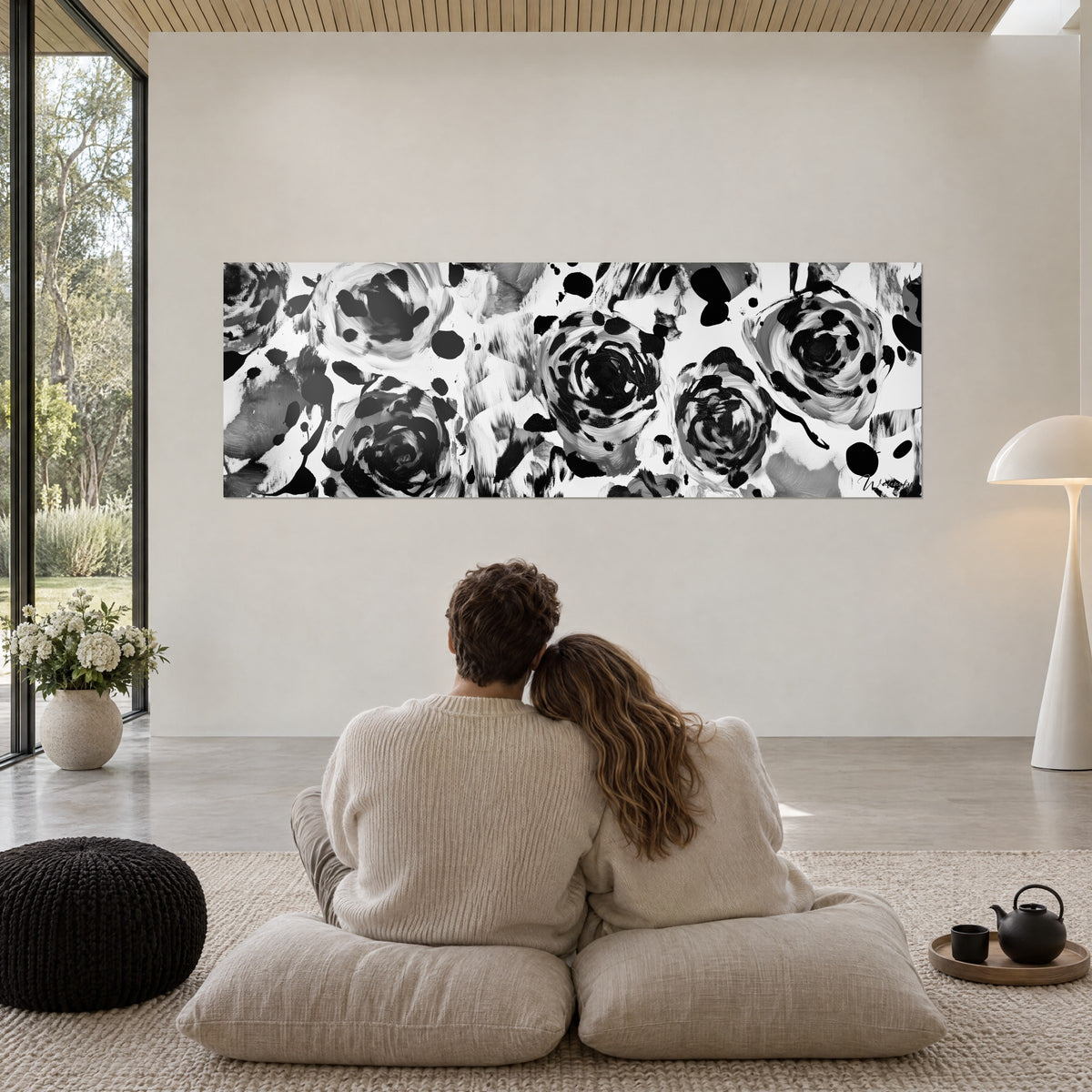 Cuadro fresco floral moteado en negro y blanco, espirales de pintura gruesa, pareja abrazada por detrás sobre cojines en el salón