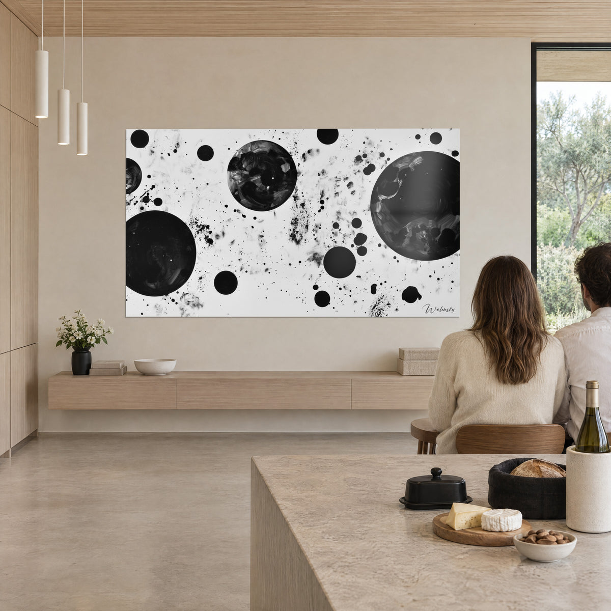 Cuadro explosión de esferas negras, manchas de pintura grises sobre blanco, dominando un rincón de comedor beige con madera clara