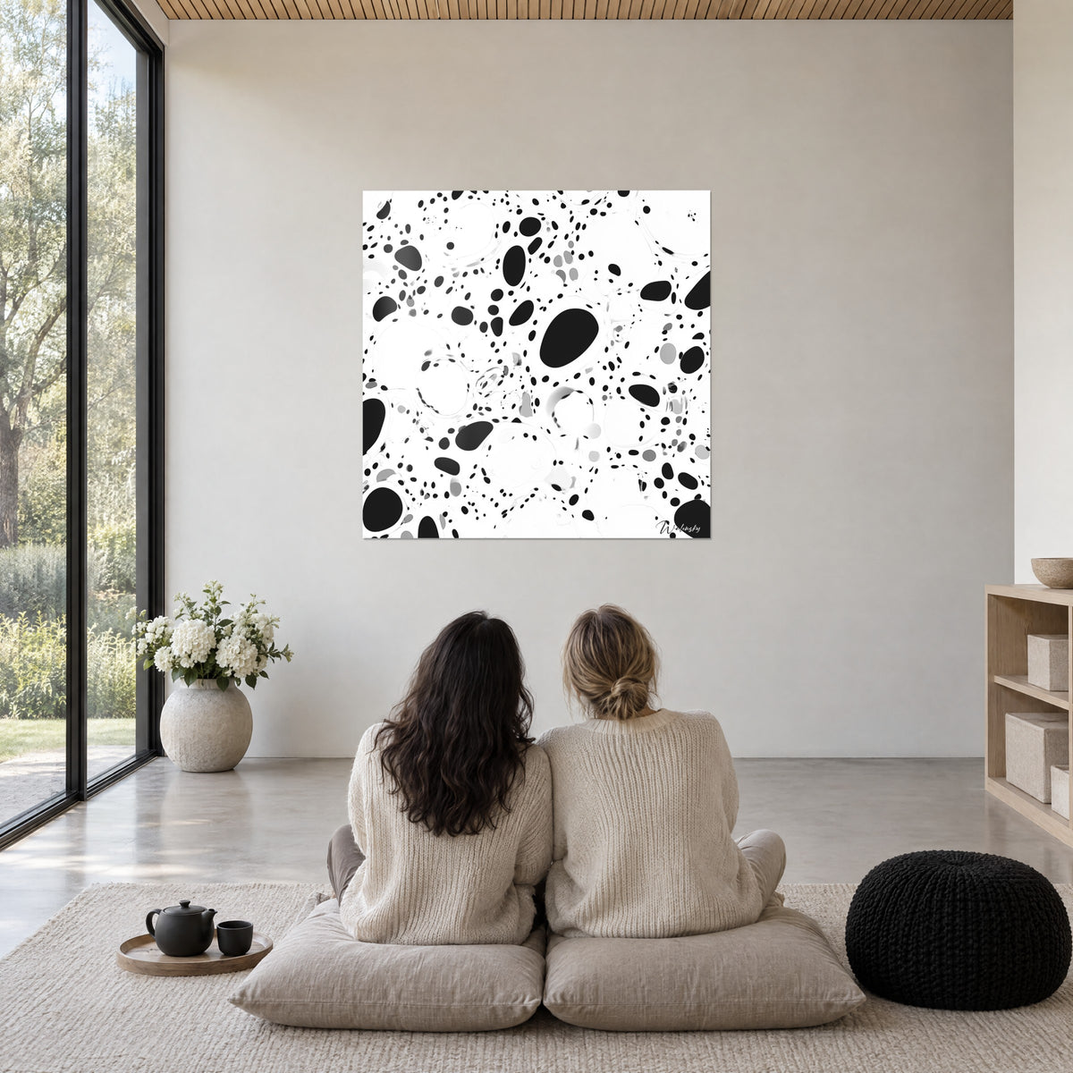 Quadro con composizione di pois e grosse macchie nere su bianco brillante, ammirato seduti su cuscini di lana chiara