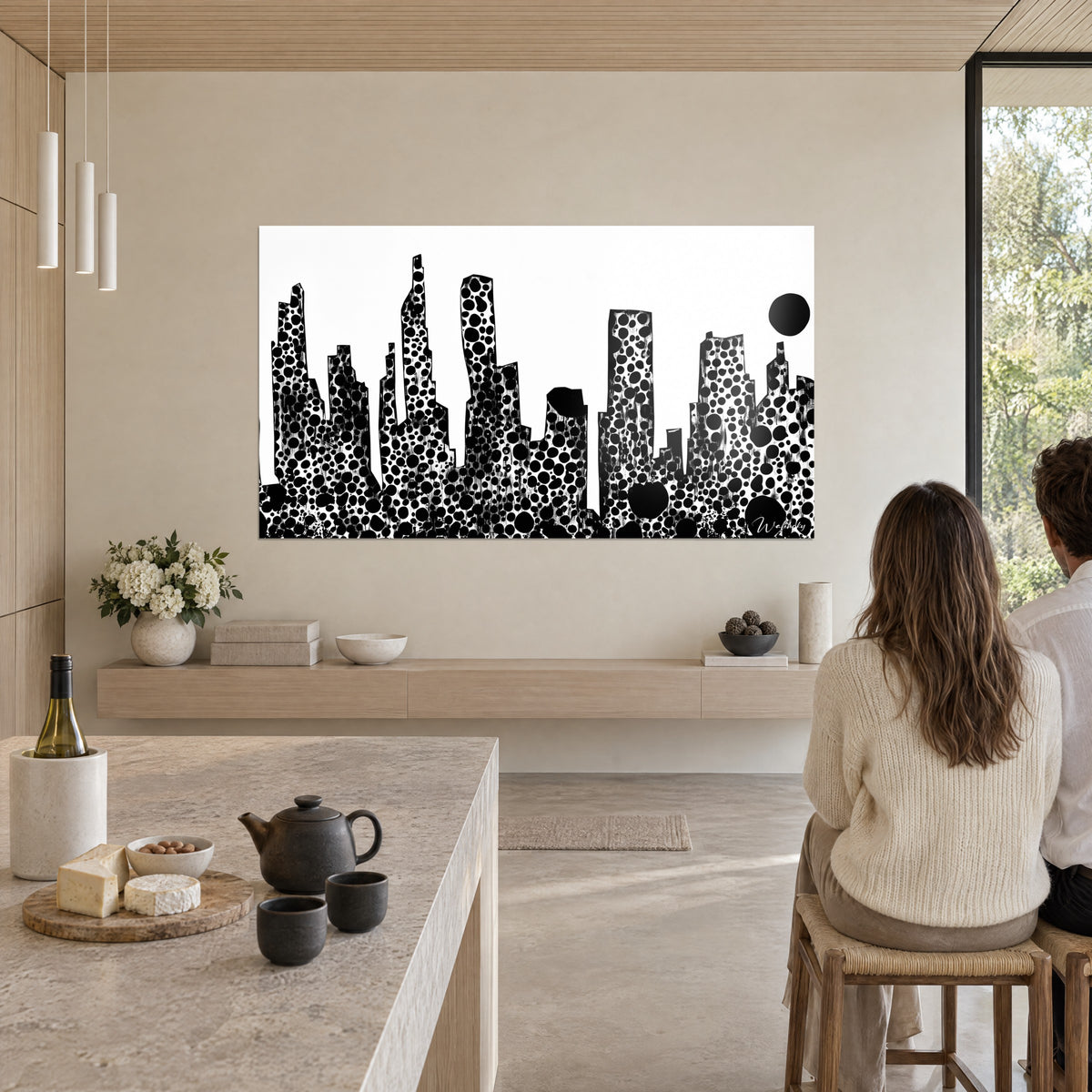 Schilderij stad met gebouwen bezaaid met zwarte inktcirkels op witte achtergrond, twee personen van achteren, open keuken in licht hout en marmer