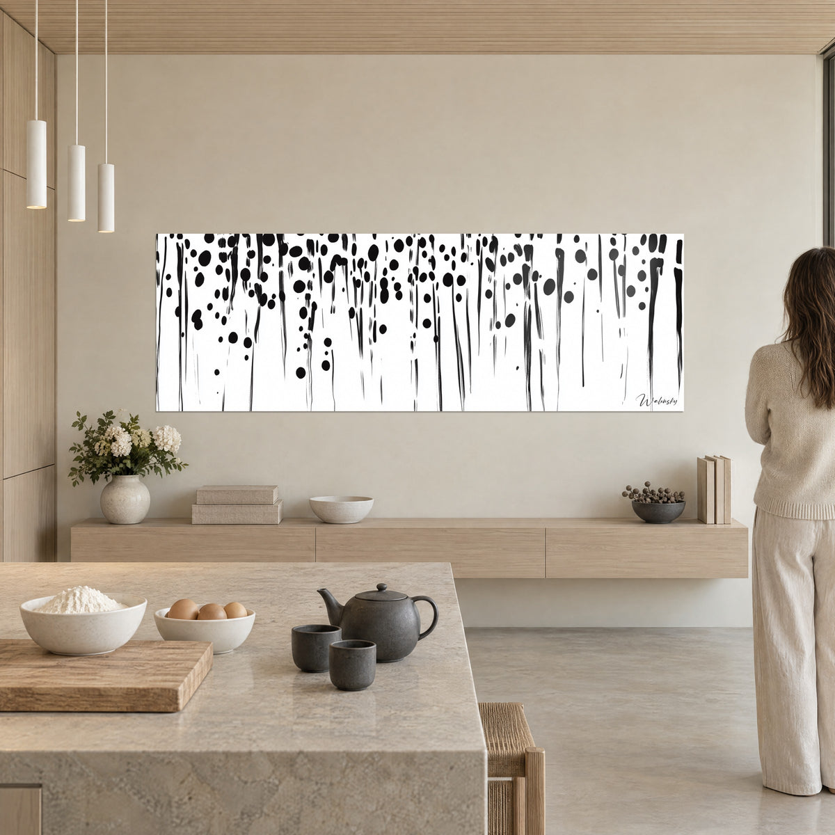 Quadro di tenda di colature nere e cerchi d'inchiostro su bianco, donna in piedi di spalle, cucina chiara in legno beige