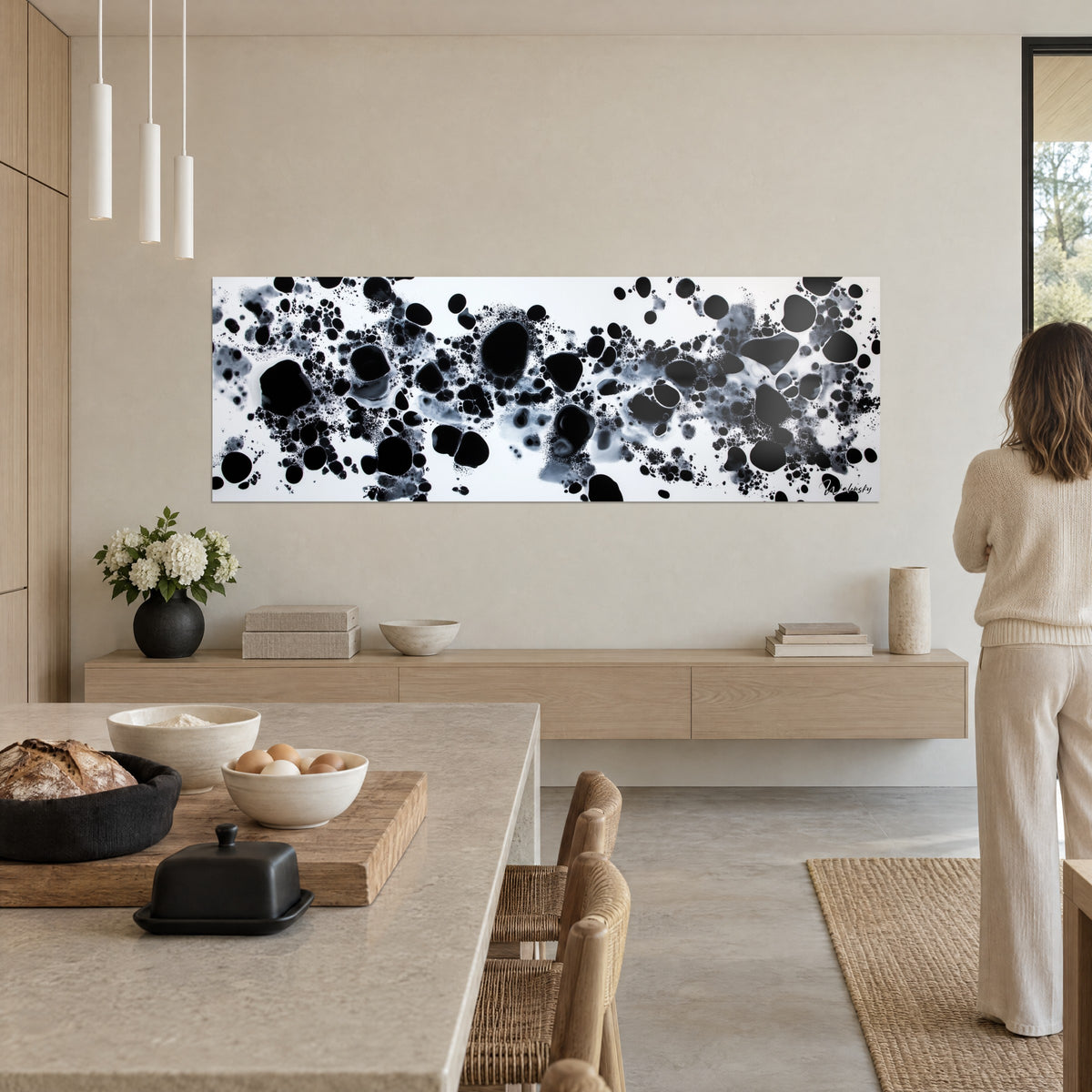 Wall art archipelago of black and grey stains splashed on white, woman seen from behind, open kitchen and a bouquet of white flowers
