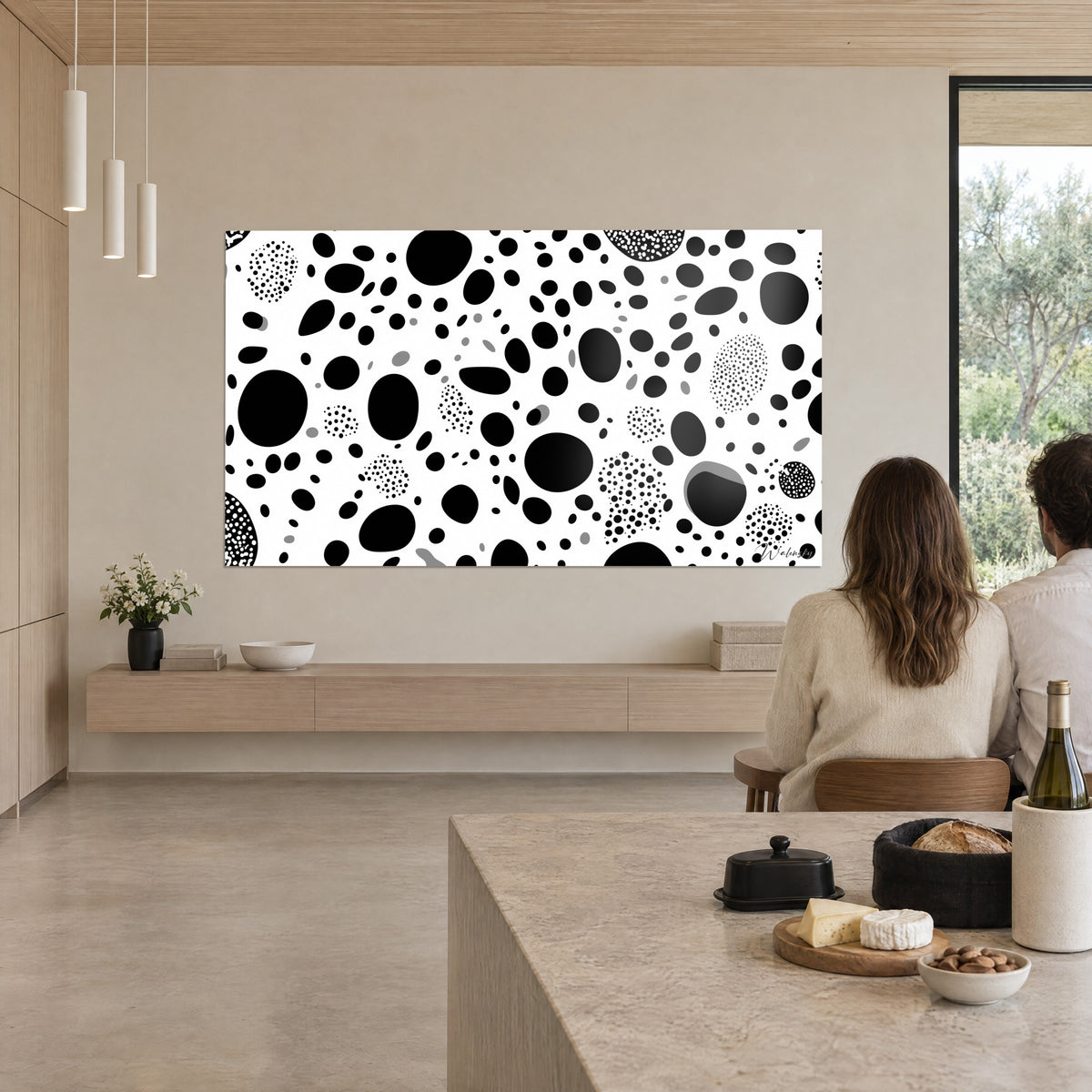 Wall art with a constellation of black blobs and white speckles, grey shadows, on the beige wall of an open kitchen overlooking the terrace