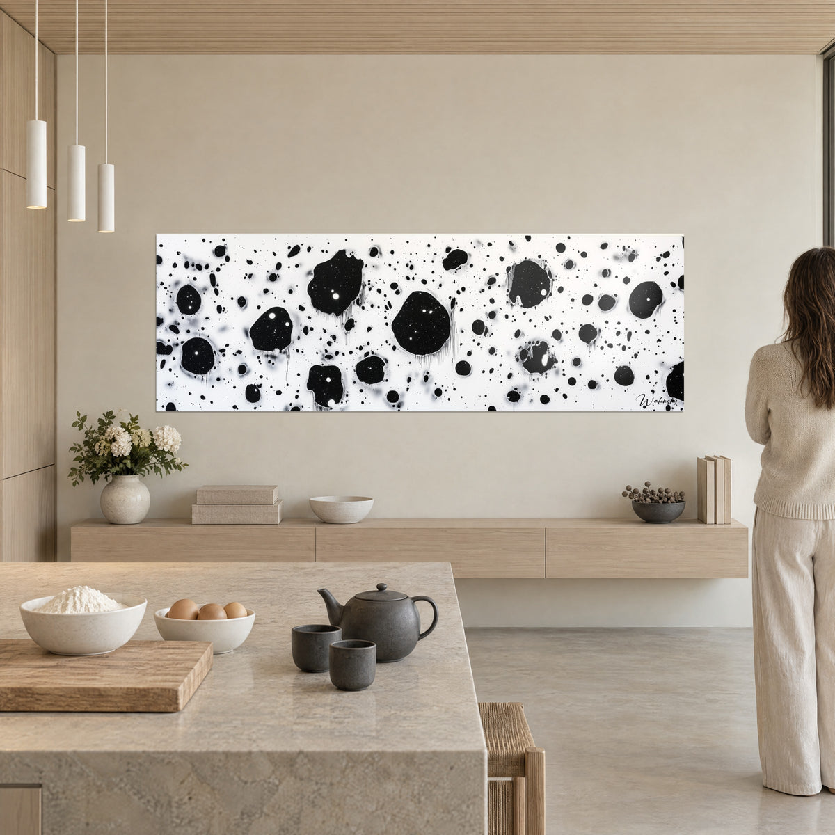 Cuadro panorámico de motas negras y blancas, grandes manchas rodeadas de finos fragmentos, en una cocina abierta beige
