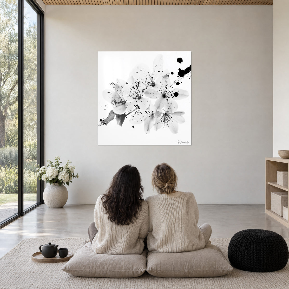 Πίνακας διάφανα άνθη αμυγδαλιάς, μαύρες κηλίδες μελανιού σε λευκό φόντο, καθαρό σαλόνι με παράθυρο, μπεζ τοίχος, μαύρα μαξιλάρια στο πάτωμα