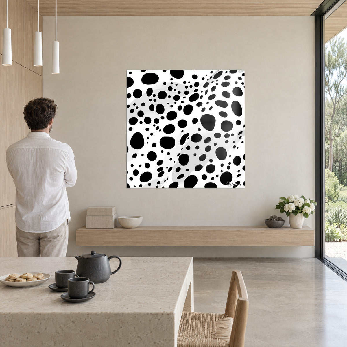 Quadro con costellazione di bolle nere su bianco brillante, uomo in camicia bianca di spalle, sopra una credenza in legno chiaro