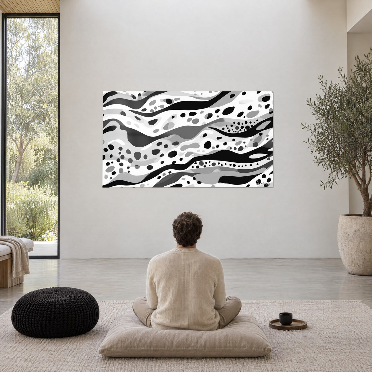 Cuadro de bandas sinuosas en negro, blanco y gris salpicadas de puntos, hombre sentado en meditación sobre un cojín, salón minimalista
