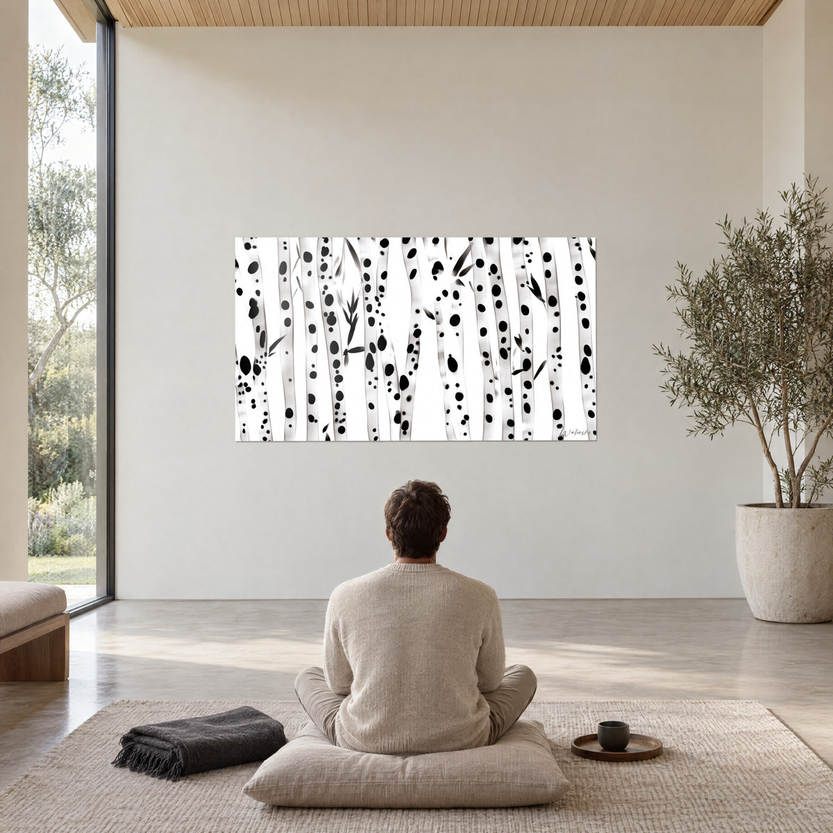 Cuadro de cañas danzantes en blanco y negro, manchas de tinta sobre troncos claros, frente a una persona sentada de espaldas sobre un cojín