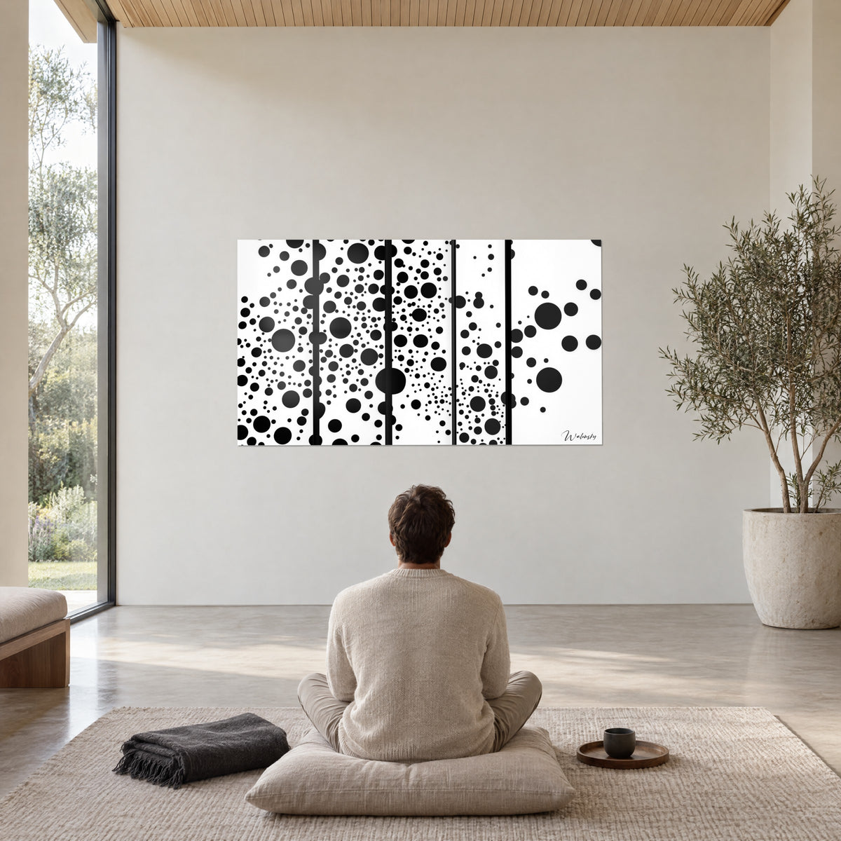 Tableau cercles noirs grands et minuscules sur cinq bandes blanches, homme de dos assis sur un coussin, olivier en pot beige