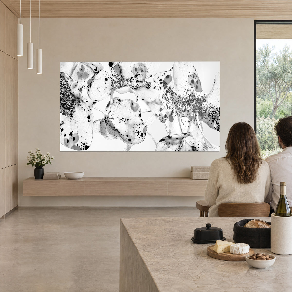 Quadro petali macchiati d'inchiostro nero su bianco, due spettatori di spalle a un tavolo di pietra, parete beige in cucina