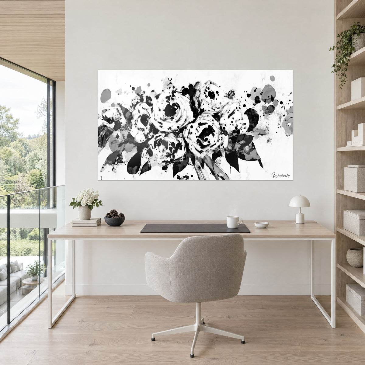 Cuadro corolas de rosas en blanco y negro, hojas oscuras y salpicaduras de tinta, colgado encima de un escritorio de madera clara
